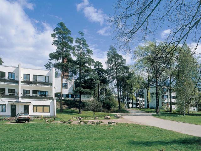 Sunilan asuinalueen rakennukset on sijoitettu väljästi metsäiseen maastoon. Terassitalo Päivölä taustallaan EKA:n huoltorakennus ja kerrostaloja. Soile Tirilä 2001